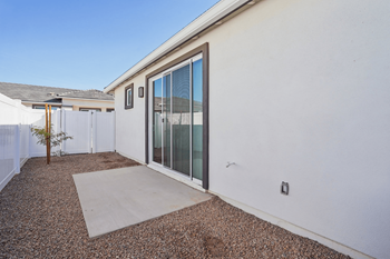 A patio area with a sliding glass door and a concrete walkway.